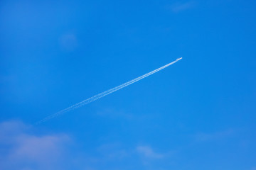 on the background of a clean blue sky, a plane fires away, leaving behind a clear white trail_