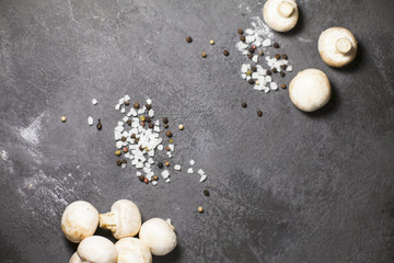 Diet, Italian Food Cooking, Vegetarian Concept. Fresh button mushrooms, sea salt grains and black pepper corns on a dark concrete background, top view