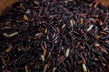 Healthy, raw black rice in the wooden bowl