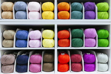 pattern of colorful different wools yarns organized by color with creativity on a shelf