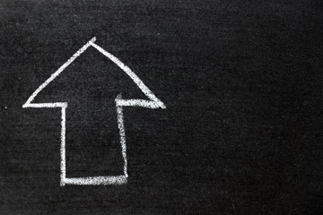 White color chalk hand drawing as arrow shape on black board background