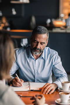 Businessman interviewing a woman at coffee shop.