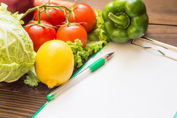 An empty notebook for recipes next to fruits and vegetables