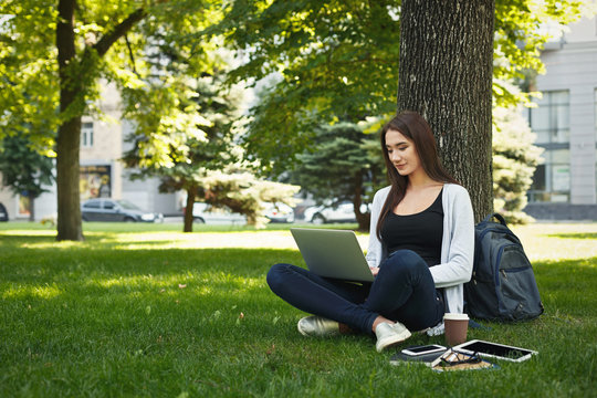 Young pensive woman using laptop in park
