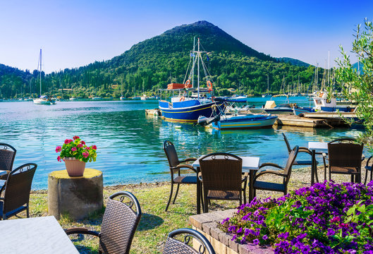 Terrace on the beach with flowers on table in Nydri village, harbour of Lefkada in Greece