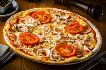Hot pizza with mushrooms, bacon, tomato and onions.