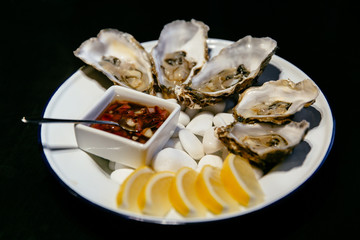 Food concept. Plate of oysters with sauce and lemon. Seafood restaurant.