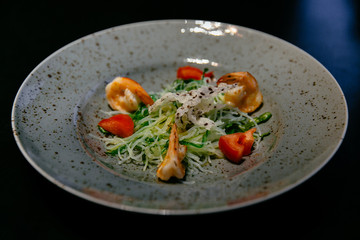 Plate of light salad with shrimp, tomatoes, rice noodles, zucchini in modern restaurant. Food concept.