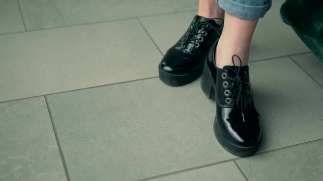 Woman walks wears black leather stylish fashionable boots and holds bag, indoor slowmotion