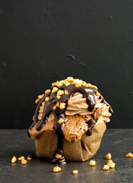 Chocolate capkake with chocolate sauce and nuts.
