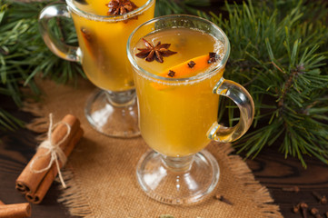 White mulled wine with various spices on a wooden background. Hot alcoholic beverage