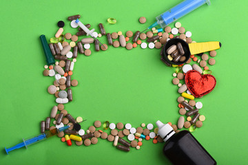Set of colorful pills scattered on green background