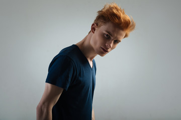 Determined. Good-looking stern red-haired young man staring and having a stylish haircut and wearing a black shirt