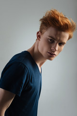 Thinking. Good-looking unsmiling red-haired young man thinking and looking in the distance and...