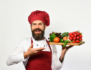 Cook with happy face in burgundy uniform holds salad ingredients.
