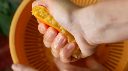 Squeezing orange juice by hands.