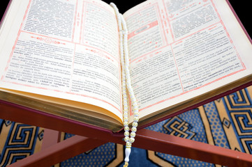 Close up of Quran with prayer beads on book rest