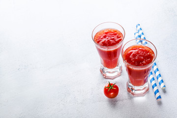 two glasses of freshly squeezed tomato juice on a marble serving board and cherry tomatoes. on a stone tableed tomato juice on a marble serving board and cherry tomatoes. on a stone table