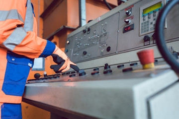 Operator in waste recycling facility operating garbage press