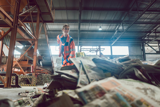 Woman in recycling center sweeping paper