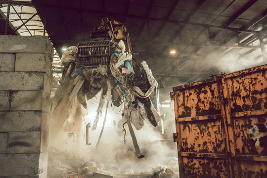 Grabber loading waste into container in recycling plant