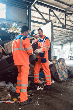 Two workers in recycling facility standing in front of a garbage heap to be sorted