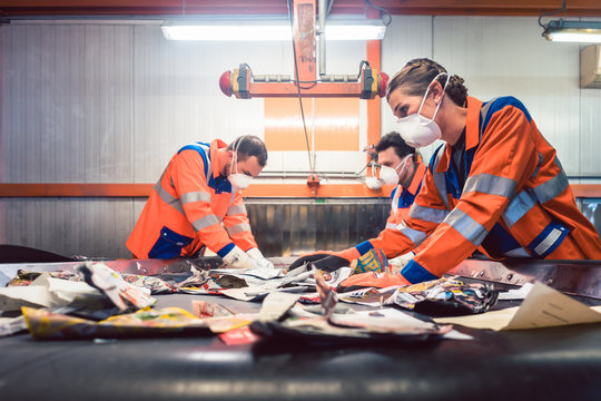 Workers in sorting room of garbage recycling facility