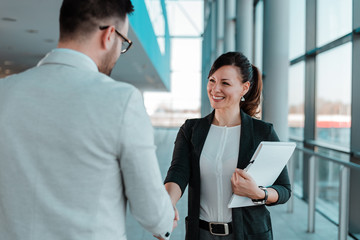 Business people handshake near the office building windows. - Powered by Adobe