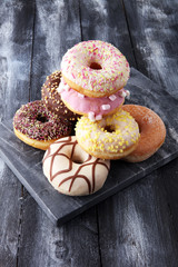 assorted donuts with chocolate frosted, pink glazed and sprinkles donuts.