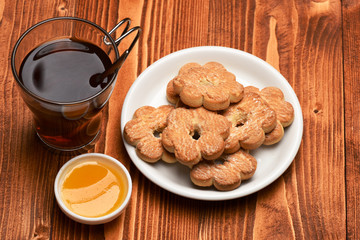 Composition of cup, honey and tiny gateau for tea time.