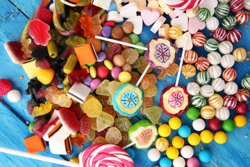 candies with jelly and sugar. colorful array of different childs sweets and treats on light blue wood background