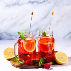 Iced tea with orange and raspberry in two glasses and mint