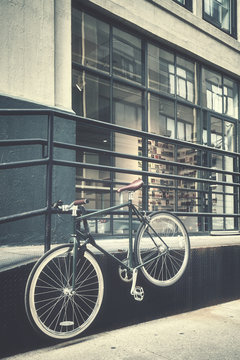 Retro stylized picture of a hanging bike by a street, New York City, USA.