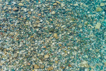 Stony bottom of the river under transparent water 