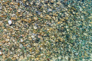 Stony bottom of the river under transparent water 