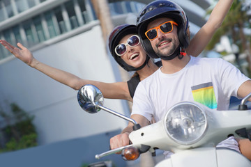 Cheerful couple riding scooter in Miami