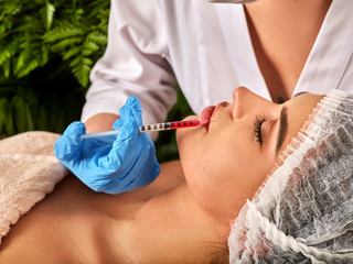 Filler injection for female face. Plastic aesthetic facial surgery by doctor in beauty clinic. Beauty woman giving injections. Green fresh plants in background.