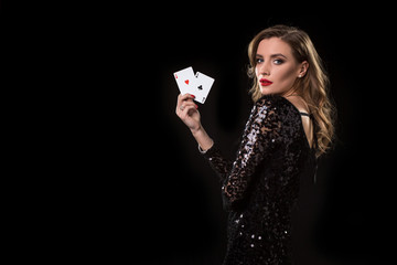 Young woman holding playing cards against a black background