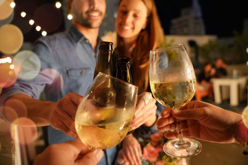 Friends drinking wine at rooftop party in summertime