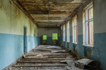 Fototapeta na wymiar Ruined Long Corridor Of Abandoned School After Chernobyl Nuclear
