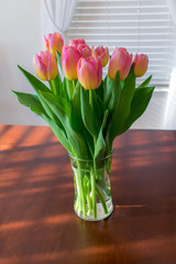 Pink Tulips in Glass Vase on Dark Wood Table