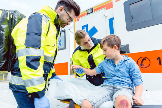 Notarzt und Sanit&auml;ter k&uuml;mmern sich um verletzten Jungen auf Transportliege