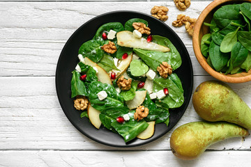 vitamin salad with spinach leaves, pear, nuts, pomegranate and feta cheese in black plate