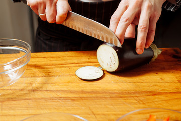 The cook cuts the eggplant.