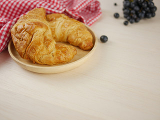 Croissant and grape close up on wooden background 