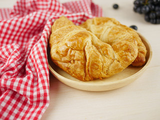 Close up croissants with grapes on beige wooden background 