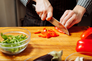 The cook chops the red pepper.