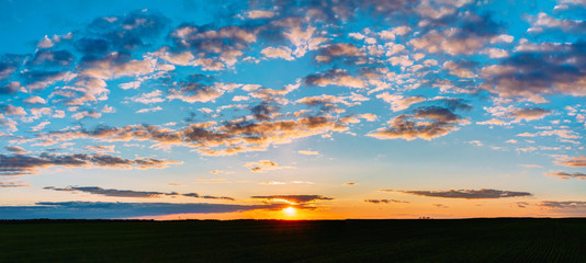Sunset Sunrise Over Field Or Meadow. Bright Dramatic Sky And Dark Ground