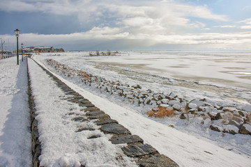 Winter landscape with snow and frozen sea near harbor and beach Urk, Dutch fishing village at the IJsselmeer