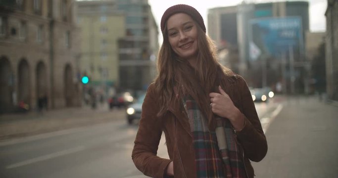 Portrait of beautiful youn woman standing in a city street and smiling to a camera.